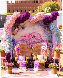 Colorful wedding archway with many floral arrangements in yellow, pink, orange, and green colors creating a vibrant path