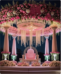 Elegant wedding stage decorated with a big pink floral chandelier composed of roses, hydrangeas, and ornamental hanging crystals with vintage style seating